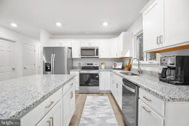a kitchen with stainless steel appliances granite countertop a sink stove microwave and refrigerator