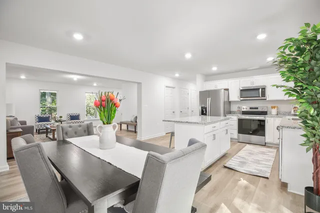 a large white kitchen with white cabinets a couches and chairs