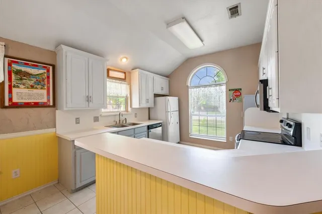 a kitchen with stainless steel appliances a sink a stove a refrigerator and a window