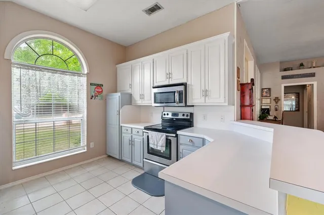 a kitchen with stainless steel appliances a stove a sink a microwave a refrigerator and cabinets