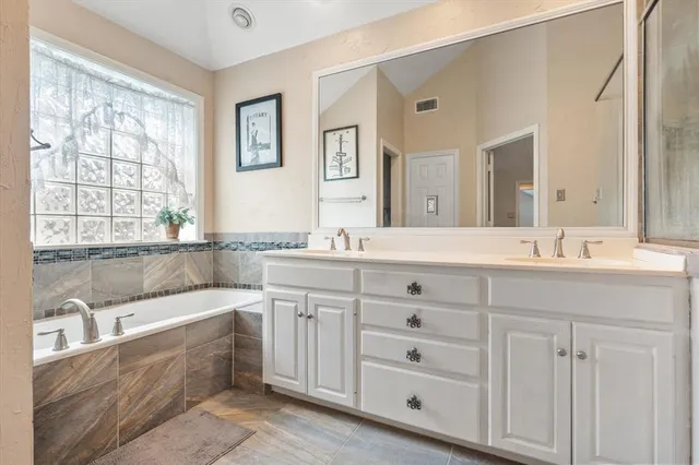 a bathroom with double vanity sink a bathtub and mirror