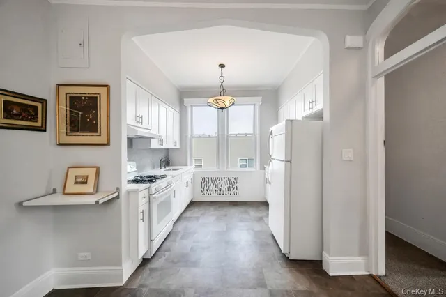 a kitchen with stainless steel appliances a refrigerator a stove a sink and a white cabinets