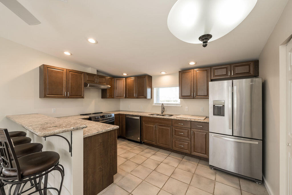 17279 Pine Tree Lane Sugarloaf, FL 33042 - Photo 16 of 33 a kitchen with stainless steel appliances granite countertop a refrigerator a stove a sink a microwave and a dining table with wooden cabinet