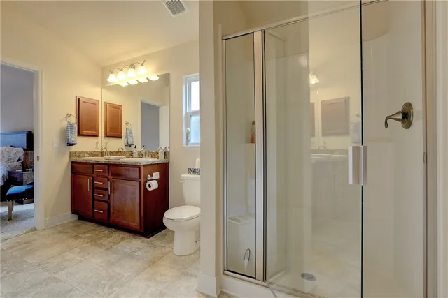 a bathroom with a granite countertop sink a toilet and shower