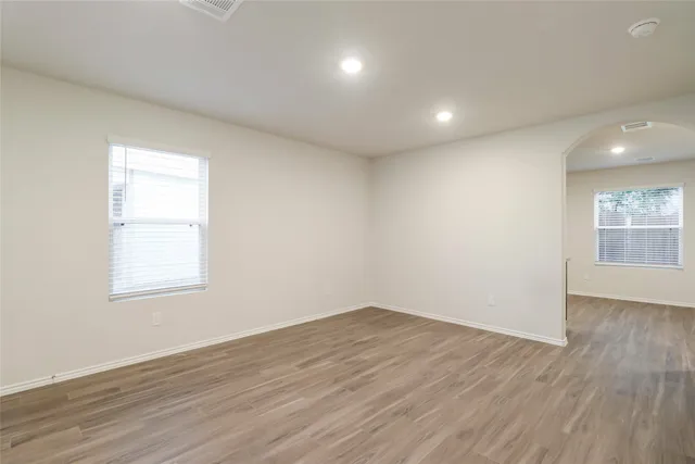 an empty room with wooden floor and windows