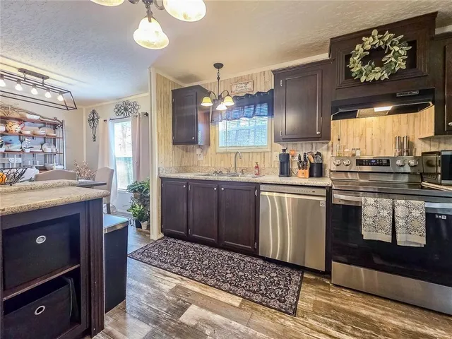 a kitchen with stainless steel appliances kitchen island granite countertop a sink stove and cabinets