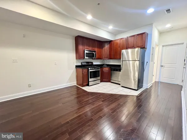 a kitchen with stainless steel appliances wooden floor sink stove refrigerator and cabinets
