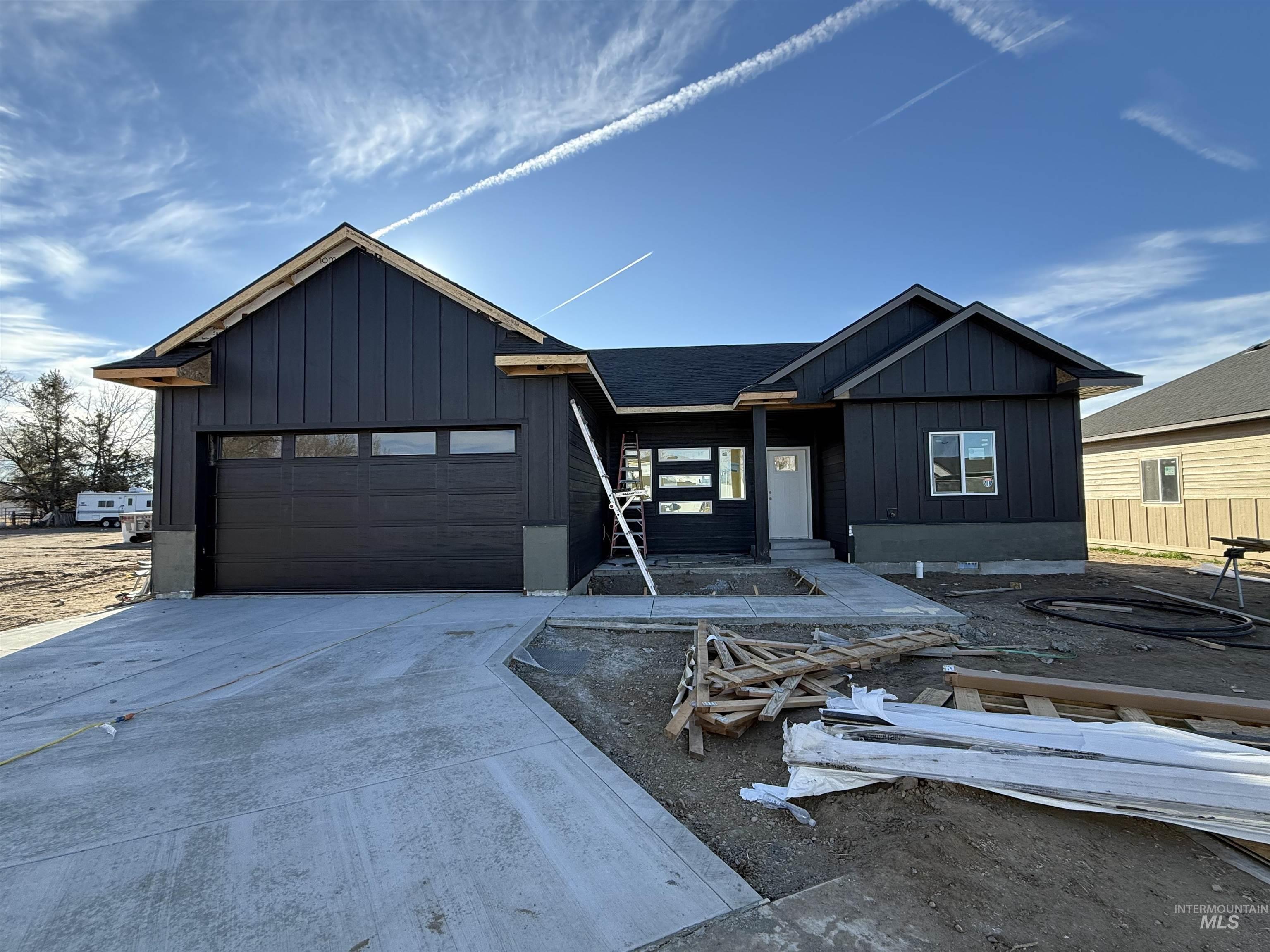 View of front facade with board and batten siding, driveway, and an attached garage