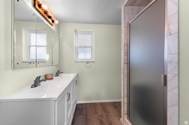 88 West 700 South Payson, UT 84651 - Photo 15 of 27 Full bathroom featuring double vanity, dark wood finished floors, a textured ceiling, a shower stall, and plenty of natural light