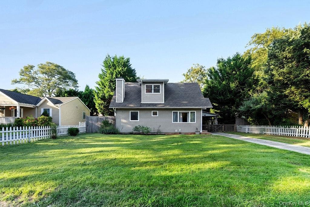 5 Liberty Street Hampton Bays, NY 11946 - Photo 3 of 17 a house that is sitting in the grass with large trees and plants