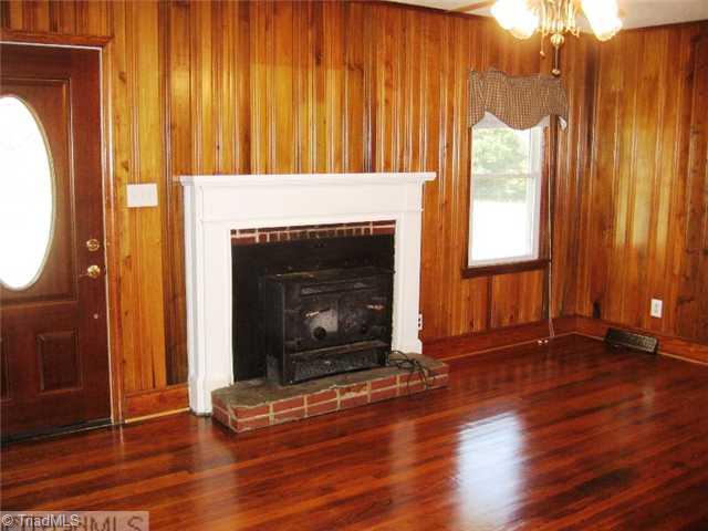 6625 Liberty Road Julian, NC 27283 - Photo 8 of 15 Living Room. Living room has hardwood floors and a wood burning stove for cold winter nights. Knotty pine panel walls which were a traditional style originally.