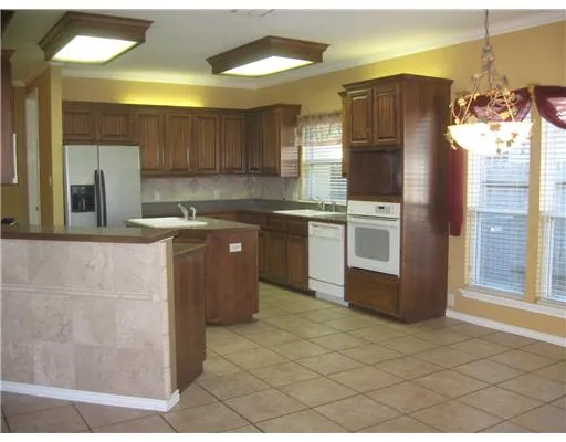 a kitchen with stainless steel appliances granite countertop a sink a stove a refrigerator a washer dryer and a dining table