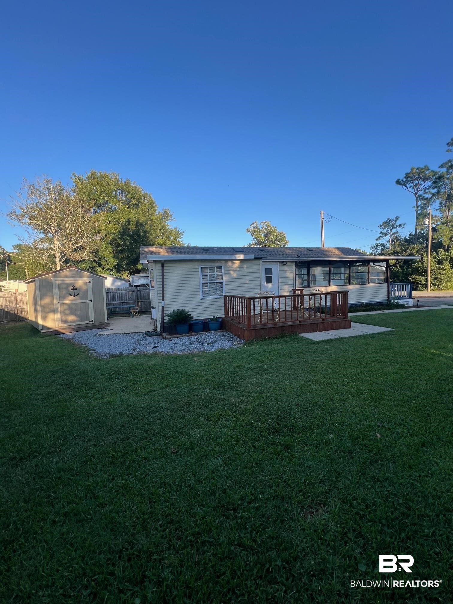 698 Escambia Loop Lillian, AL 36549 - Photo 14 of 16 Rear view of property featuring a deck, a lawn, and a storage unit