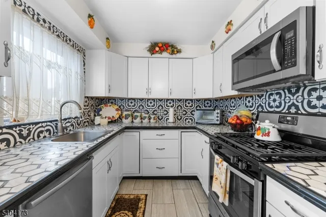 a kitchen with stainless steel appliances granite countertop a sink stove and cabinets