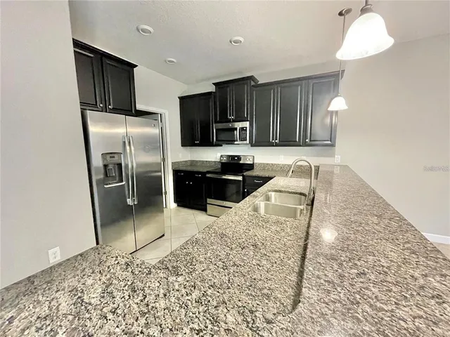 a kitchen with stainless steel appliances kitchen island granite countertop a refrigerator stove and oven