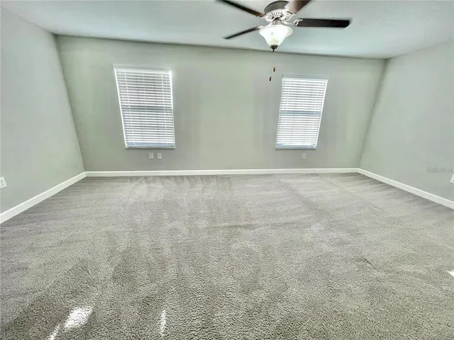 an empty room with windows and fan