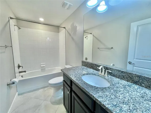 a bathroom with a granite countertop sink toilet and shower