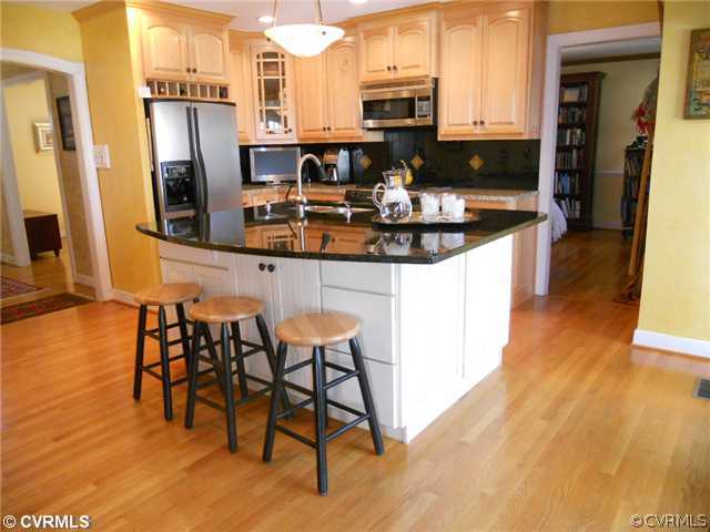 2551 Kentford Road Midlothian, VA 23113 - Photo 5 of 12 a kitchen with stainless steel appliances granite countertop a stove top oven a sink a dining table and chairs with wooden floor