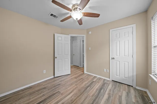 an empty room with wooden floor chandelier fan and closet area
