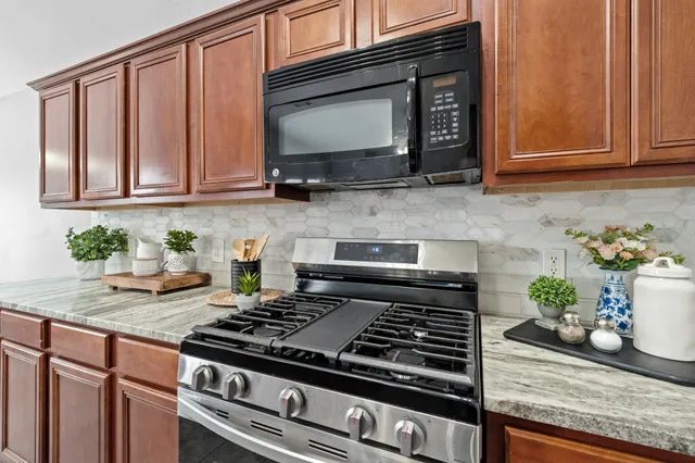 a kitchen with granite countertop stainless steel appliances stove microwave and cabinets