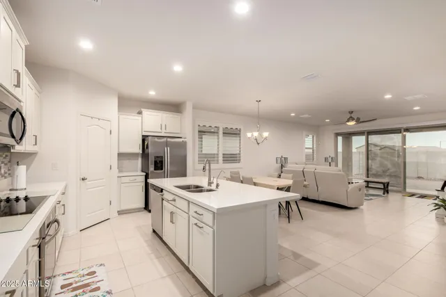 a large white kitchen with stainless steel appliances kitchen island granite countertop a lot of counter space and a refrigerator