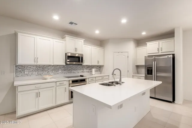 a kitchen with a sink a refrigerator and white cabinets