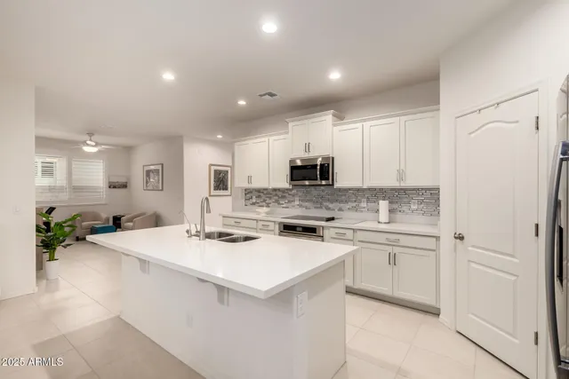 a kitchen with a sink a stove a refrigerator and white cabinets