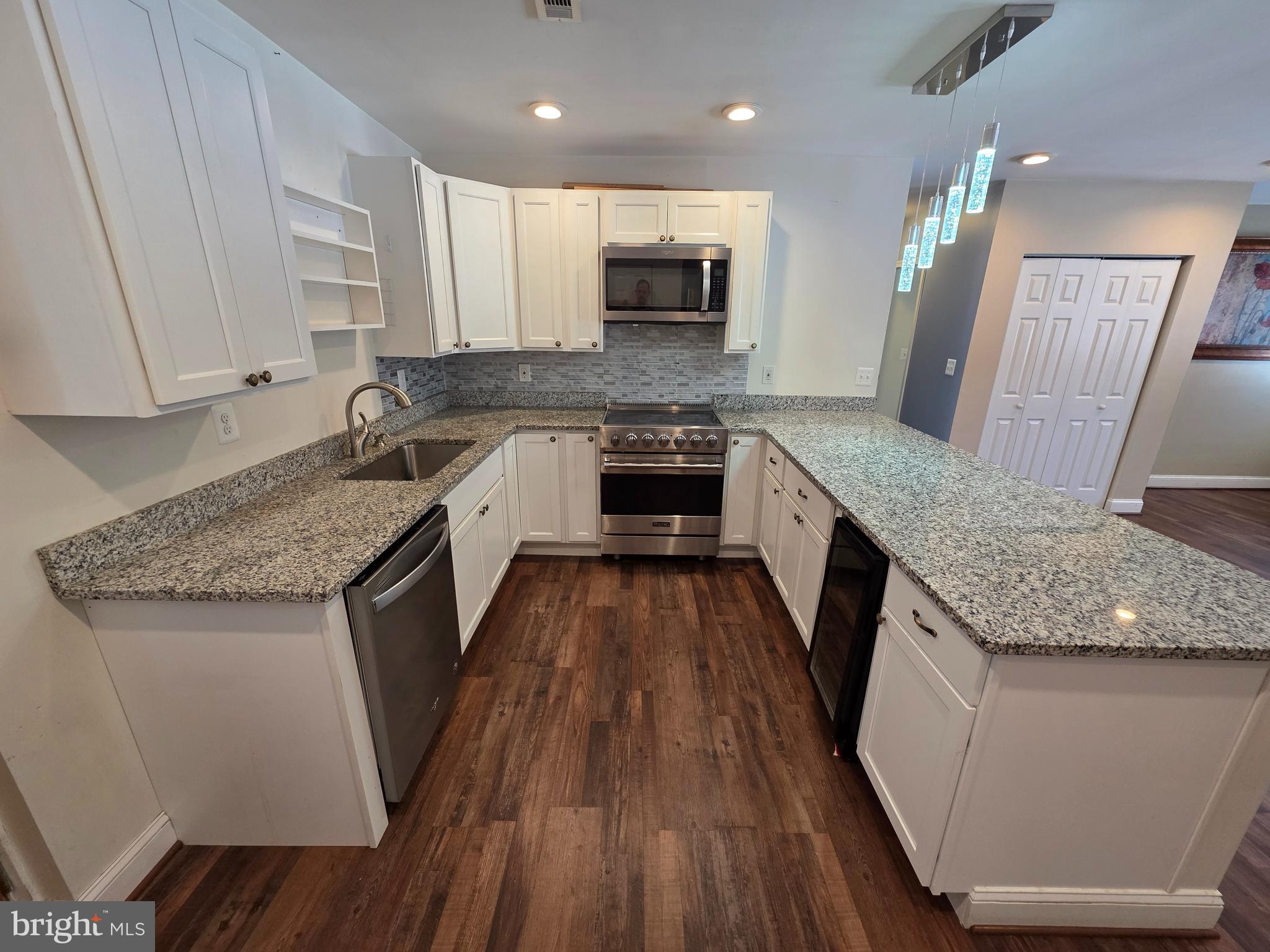 1342 Edna Road Pasadena, MD 21122 - Photo 11 of 31 a large kitchen with granite countertop a large counter top space a sink a stove a refrigerator and cabinets