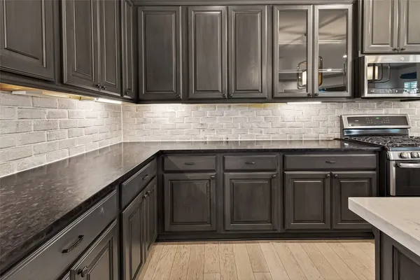 a kitchen with stainless steel appliances granite countertop a sink dishwasher stove and cabinets with wooden floor