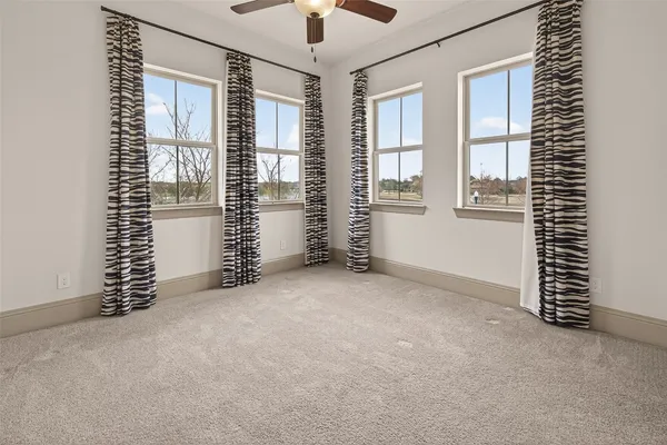 an empty room with windows and chandelier fan