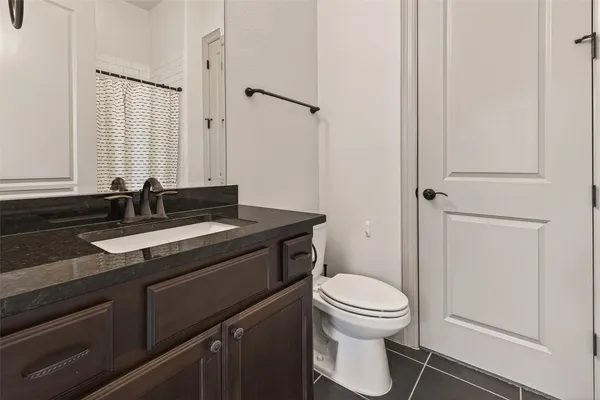 a bathroom with a granite countertop sink toilet and a mirror