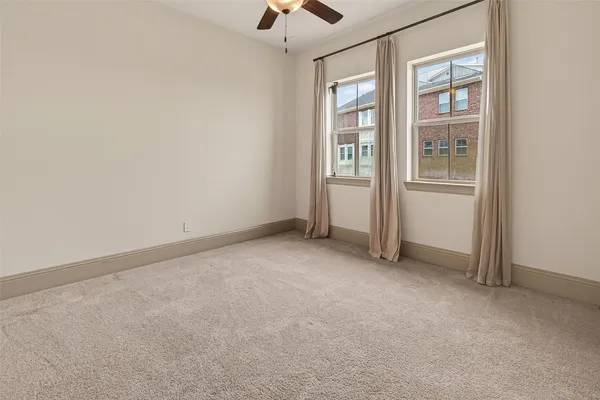 an empty room with chandelier fan and windows