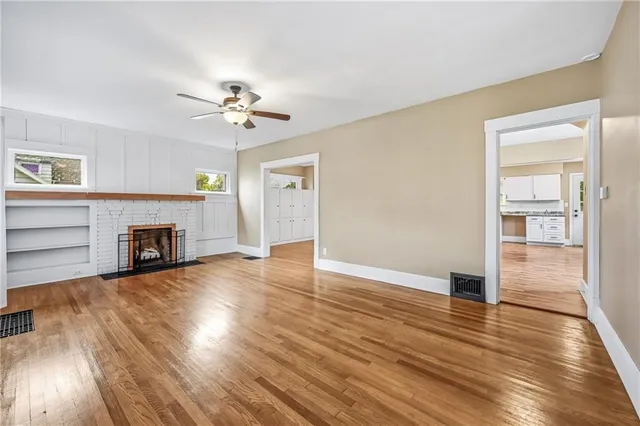 an empty room with wooden floor fireplace and a window