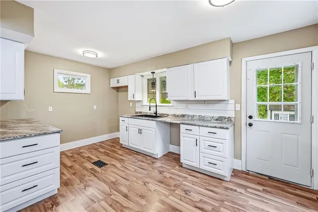 a kitchen with granite countertop white cabinets and window