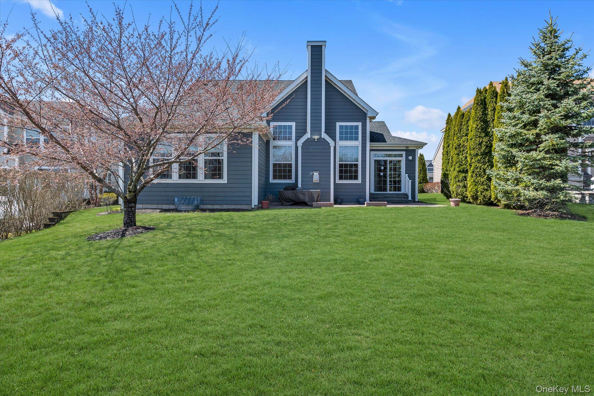 390 Stonecrop Road Riverhead, NY 11901 - Photo 22 of 24 a view of a yard in front of a brick house with plants and large tree