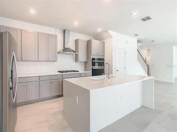 a large white kitchen with kitchen island a sink a stove a refrigerator and white cabinets