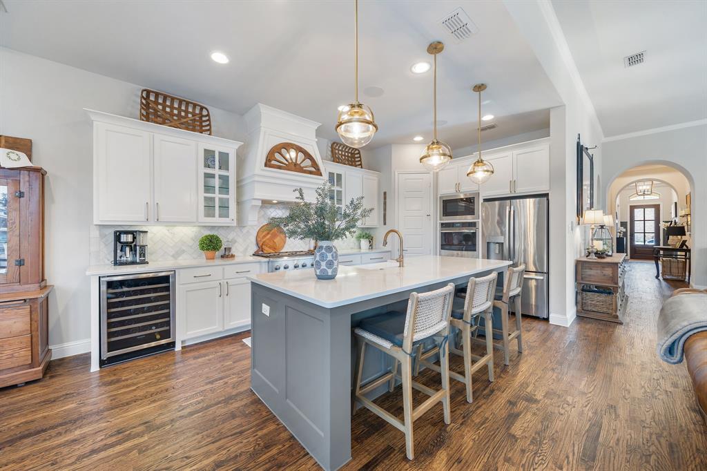 16509 Prairie Oak Road Frisco, TX 75033 - Photo 11 of 39 a kitchen with stainless steel appliances kitchen island granite countertop a stove a sink a refrigerator and white cabinets with wooden floor