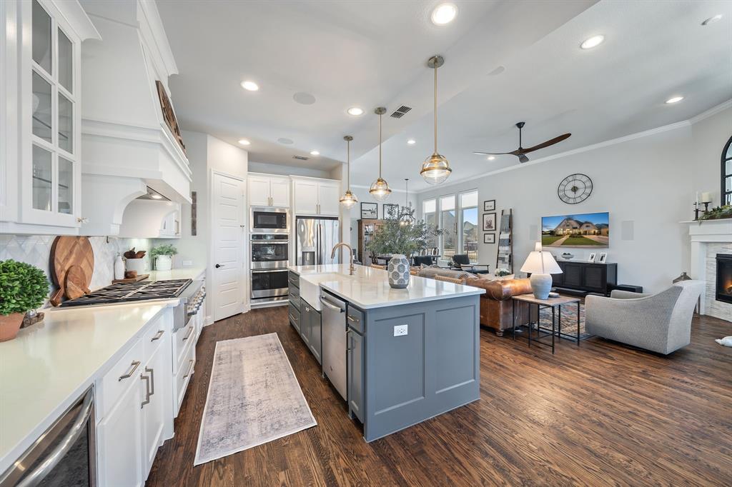 16509 Prairie Oak Road Frisco, TX 75033 - Photo 12 of 39 a large kitchen with stainless steel appliances kitchen island granite countertop a large center island a sink a stove and a wooden floors