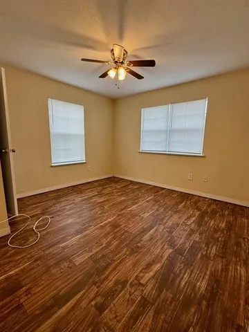 a view of an empty room with window and chandelier fan