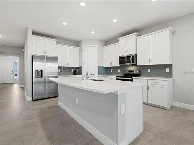 a kitchen with granite countertop white cabinets and stainless steel appliances