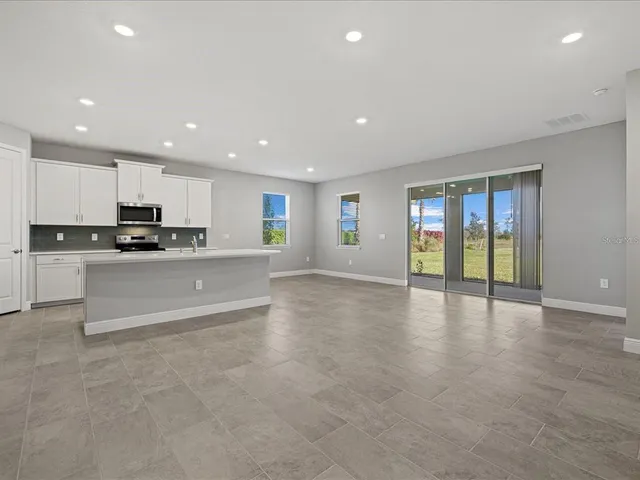 a large kitchen with stainless steel appliances granite countertop a large counter top and a stove with wooden floor