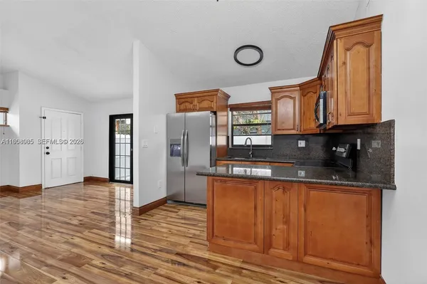 a view of a kitchen with stainless steel appliances granite countertop a refrigerator and a stove top oven