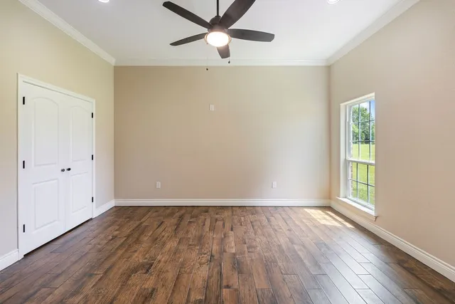 an empty room with wooden floor a ceiling fan and windows