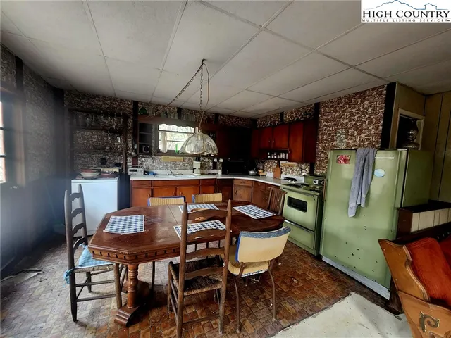 a kitchen with stainless steel appliances kitchen island granite countertop a table chairs and a refrigerator