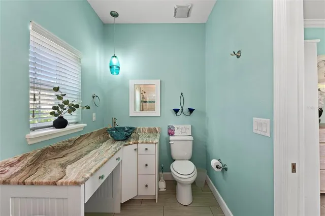a bathroom with a granite countertop toilet sink and mirror