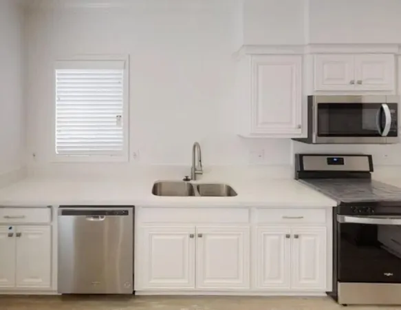 a kitchen with white cabinets and sink