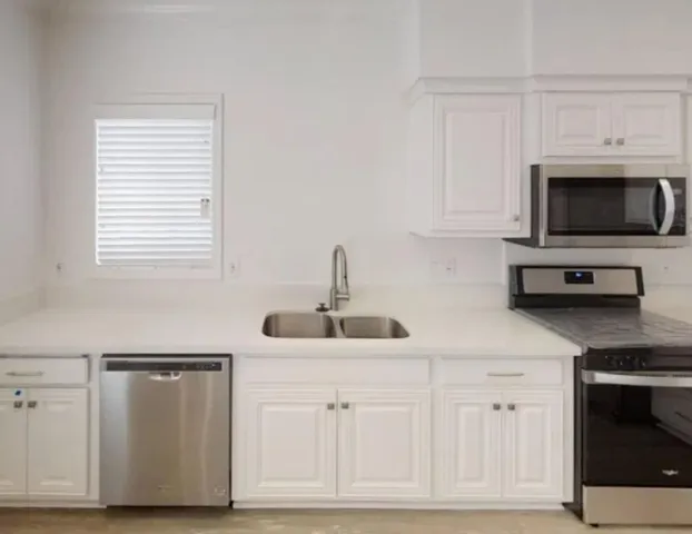 a kitchen with white cabinets and sink