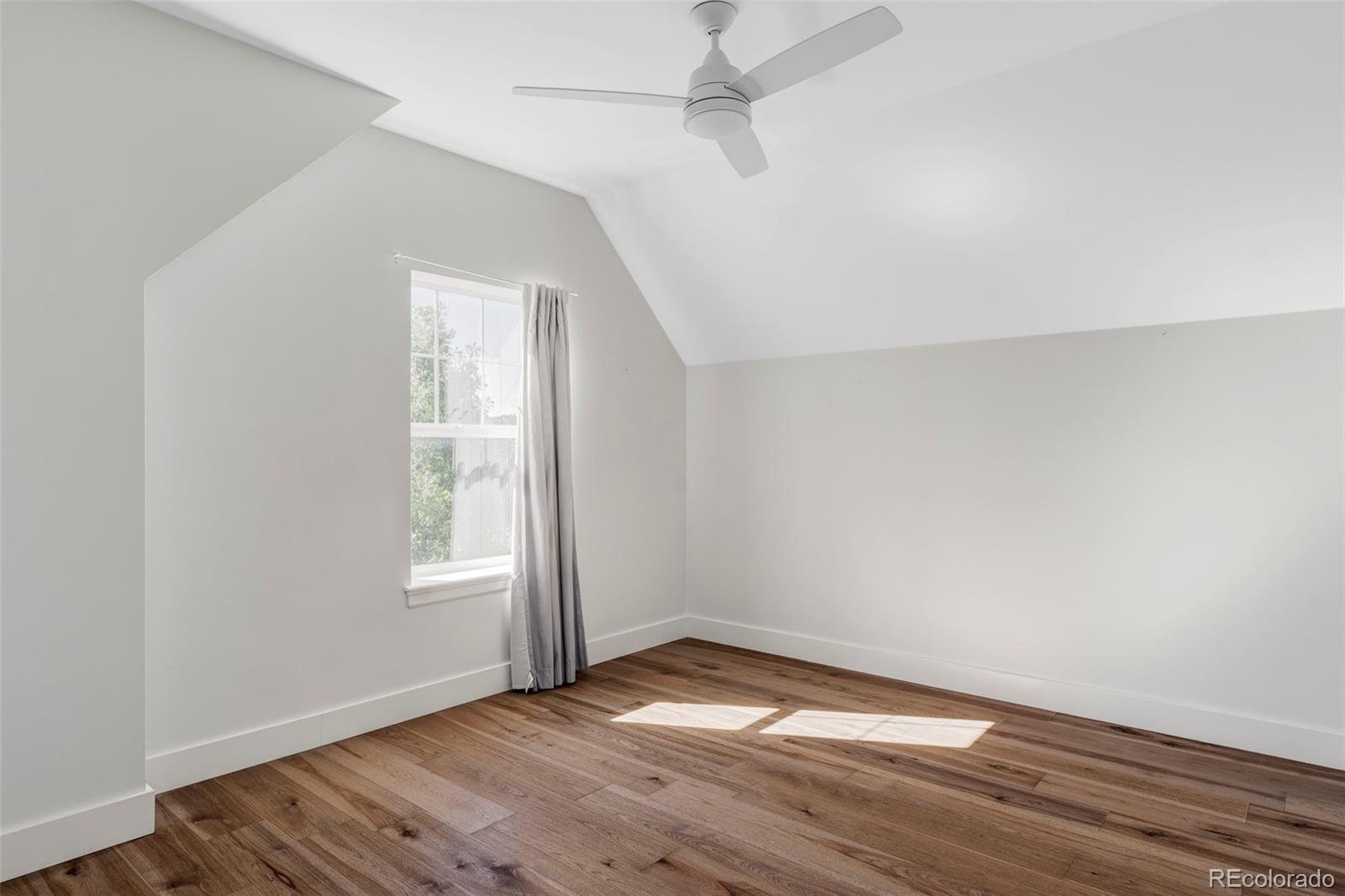 2908 Ironton Street Denver, CO 80238 - Photo 20 of 30 an empty room with wooden floor fan and windows