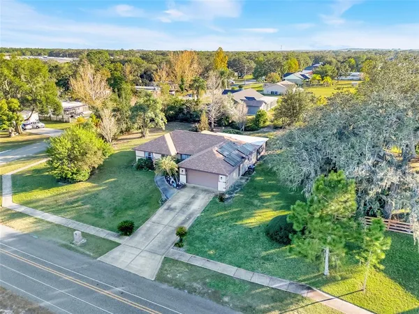 an aerial view of residential houses with outdoor space and trees