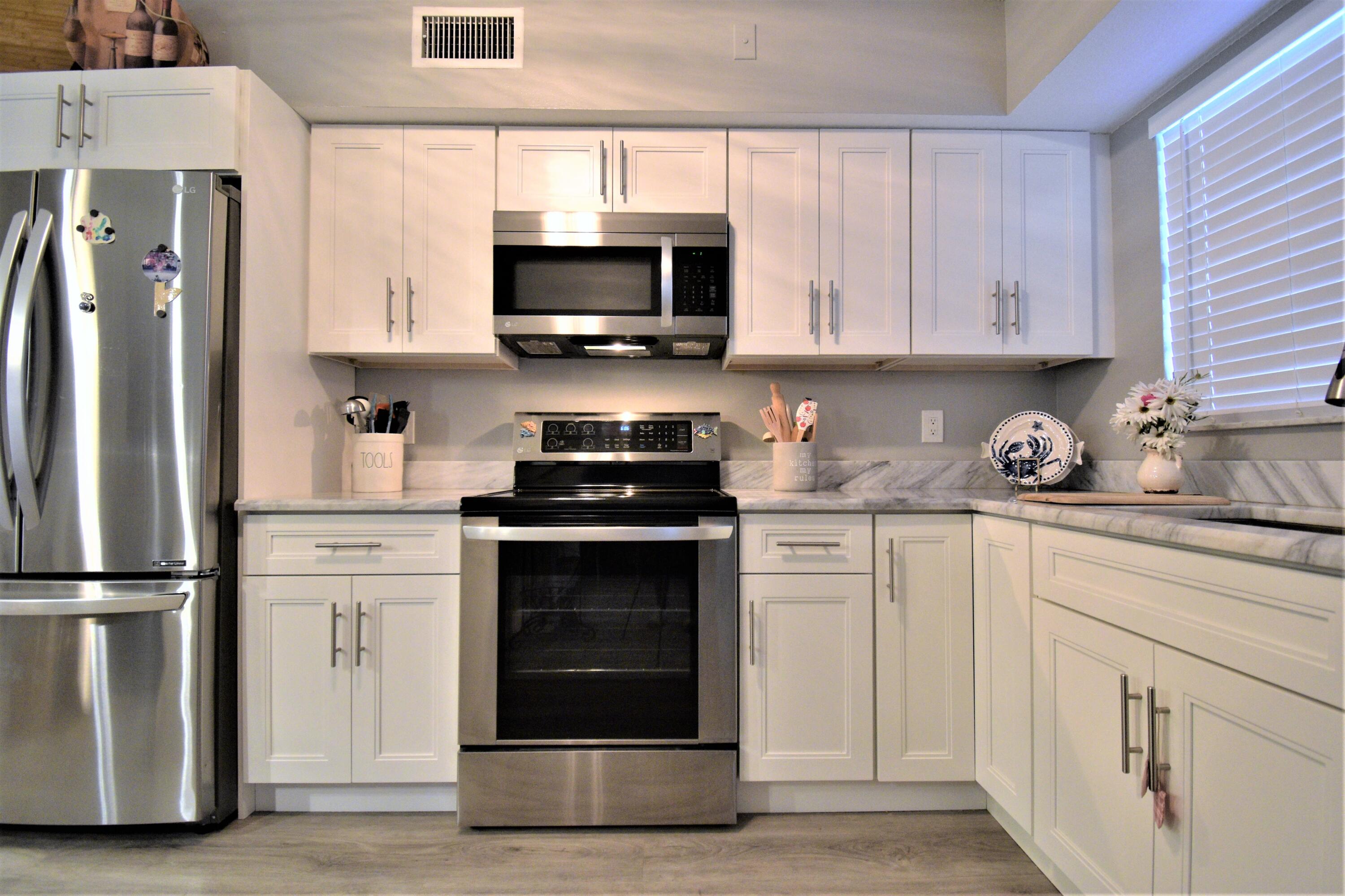 a kitchen with white cabinets stainless steel appliances and a window